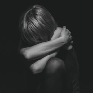 A dramatic black and white portrait capturing deep emotion and solitude in a studio setting.